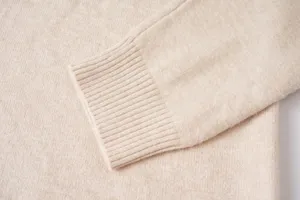 Detalle en primer plano de la manga del jersey beige de hombre, textura suave y puño acanalado.