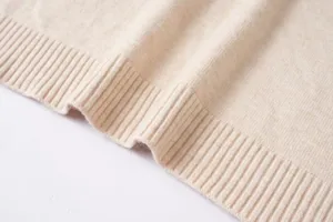 Primer plano de la textura del tejido del suéter beige y el detalle del dobladillo fino.