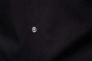 Primo piano dettaglio di tessuto per camicia nera da uomo con cuciture e bottone. Bella vista.