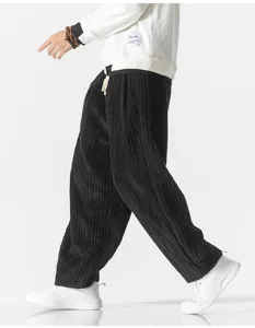 Detailed view of men's black corduroy casual pants, loose harem style texture shot.