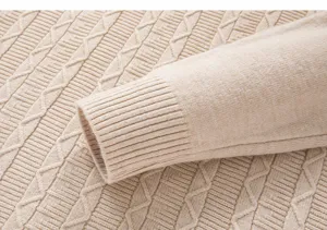 Close-up detail of men's cable knit sweater sleeve, soft texture and ribbed cuff design.