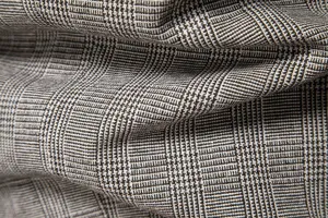 Dettaglio tessuto abito uomo primo piano, classico motivo texture quadri retro nero grigio.