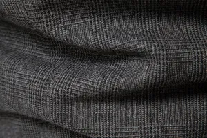 Primo piano della texture del tessuto del blazer in lana a quadri grigio scuro da uomo, dettagli.