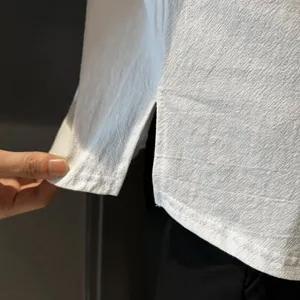 Close-up detail of white cotton linen mens shirt hem, showing fabric texture and side split.