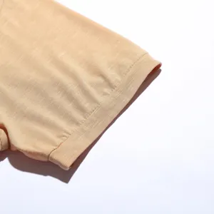 Nahaufnahme des hellorangen gestrickten Kurzarm-T-Shirt-Bündchens mit Stoffstruktur.