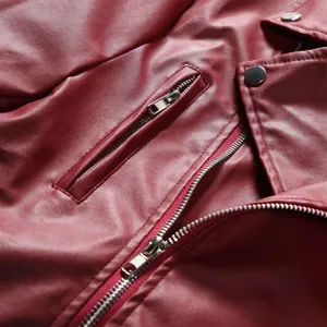 Close-up detail shot of wine red faux leather jacket zipper and pocket design style.
