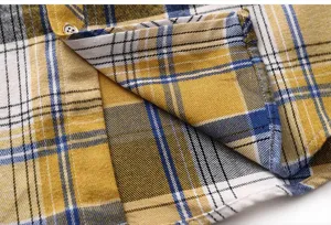 Close-up detail of men's yellow and blue plaid shirt fabric, placket and button texture.