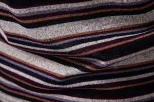 Close up view of men knit striped t shirt fabric, showing soft texture and multi color stripes.