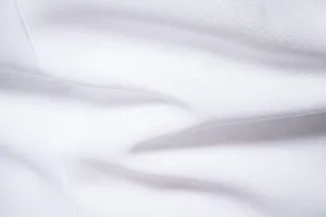 Primo piano del tessuto per abito bianco con trama twill premium e pieghe morbide.