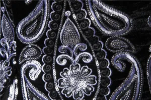 Close-up of black velvet fabric with intricate silver thread embroidery and sparkling sequins.