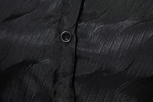 Primer plano del tejido jacquard negro texturizado y detalle de botones de la camisa de hombre.