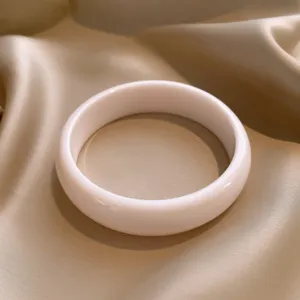 Elegante roomwitte ronde hars armband gepresenteerd op een beige satijnen achtergrond