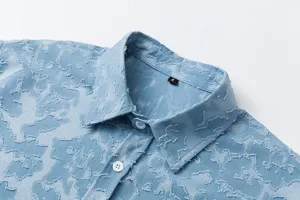 Dettaglio del colletto di camicia uomo a maniche corte vissuta, texture casual blu vintage.