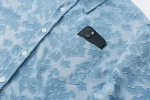 Primo piano dettagliato della camicia a maniche corte azzurra strutturata con taschino.