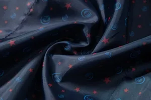 Fabric detail close-up showing dark blue material with red star and blue swirl print.