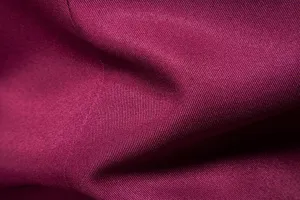 Dettaglio del tessuto della giacca da uomo con trama twill bordeaux di alta qualità.