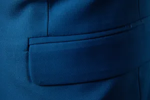 Men's suit jacket detail shot, featuring professional blue twill fabric and refined pocket design.