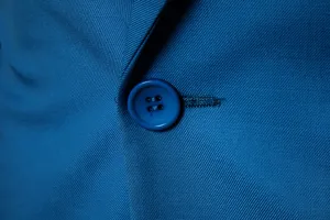 Close up detail of mens blue business casual suit jacket button and fabric texture.