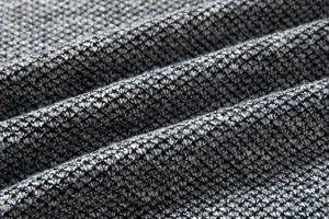 Vista dettagliata del tessuto del maglione lavorato a maglia da uomo con motivo grigio.