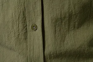Close-upweergave van de stoftextuur en het knopdetail van het casual herenhemd.