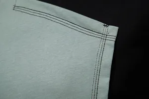 Vue rapprochée des coutures contrastées et de la texture du tissu pour haut homme.