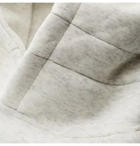 Close-up of light grey heather hoodie fabric with neat stitching, casual menswear detail