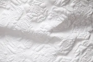 Detailed view of white fabric featuring embossed rose floral pattern for men suit design texture.