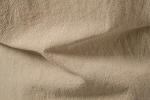 Detailopname van kaki katoen-linnen stofstructuur met natuurlijke rimpels en ademend materiaal.