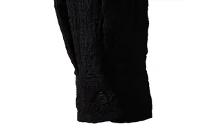Detailed view of men's black long sleeve shirt cuff with exquisite jacquard fabric and button.