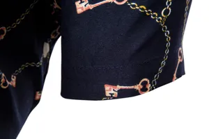 Detailansicht eines Freizeithemds mit vintage goldener Kette und Schlüsseldruck.