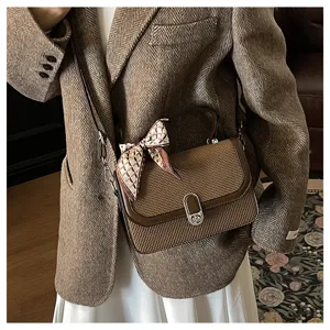 Detailed shot of the brown woven crossbody bag with stylish scarf and turn-lock hardware.