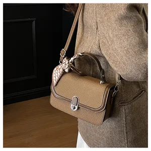 Detail view of a chic woven small square shoulder bag with elegant scarf and metal lock.