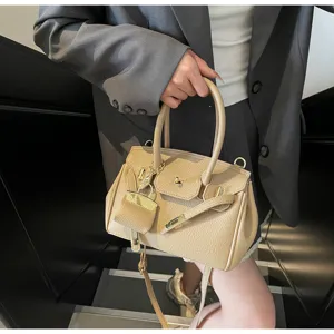 Vue détaillée du sac à main élégant en cuir abricot avec cadenas en métal et bandoulière.