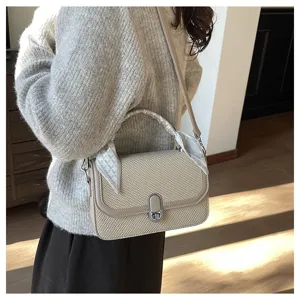 Detailed view of women woven shoulder bag with chic handle scarf and metallic clasp detail.