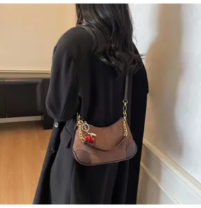 Detailed view of the brown suede underarm shoulder bag with chic cherry pendant and chain.