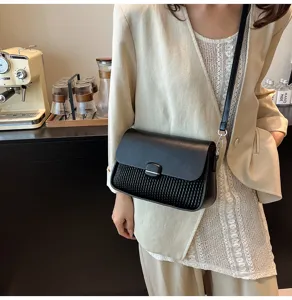 Detail view of the black woven leather shoulder bag, commuter style small square underarm bag.
