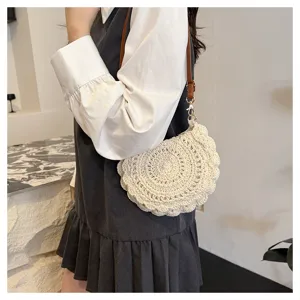 Primer plano de un elegante bolso cruzado de paja tejida a mano llevado por un modelo.