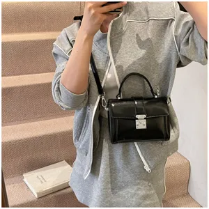 Black glossy small square box bag detail shot, classic crossbody shoulder design with metal lock.