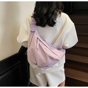 Detail view of the purple nylon crossbody dumpling bag showing wide strap and back fit.