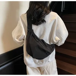 Black nylon crossbody dumpling bag worn on back, casual commuter sling bag with wide strap.