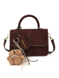 Chic brown suede top handle handbag with cute teddy bear keychain and stylish hanging tag for women.