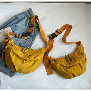Detail shot of yellow nylon crossbody dumpling bag with wide strap and buckle.