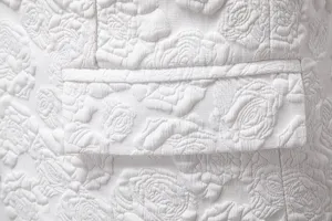 Close-up detail of white floral jacquard fabric and pocket flap on a stylish men suit blazer.