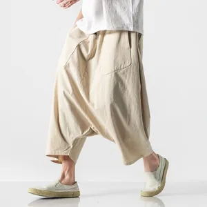 Close-up of men's loose beige harem pants featuring a low crotch design and breathable fabric.