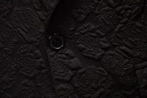 Close-up detail of men's black suit fabric featuring elegant rose jacquard and button.