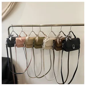 Detailed shot of multi-color minimalist handbags hanging on a metal rack with stylish silk scarves.