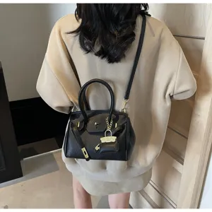 Vue détaillée d'un sac à main noir texturé avec cadenas et sangle sur le dos du modèle.