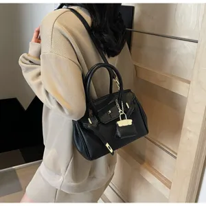 Vue détaillée du sac à main en cuir noir texturé avec cadenas métallique et poignées.