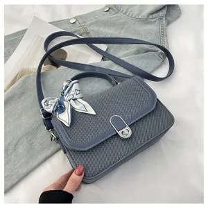 Detail shot of blue denim texture handbag showcasing exquisite lock closure and stylish silk scarf.