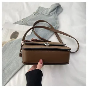 Detail shot of stylish brown women's shoulder bag featuring textured flap and metal lock.